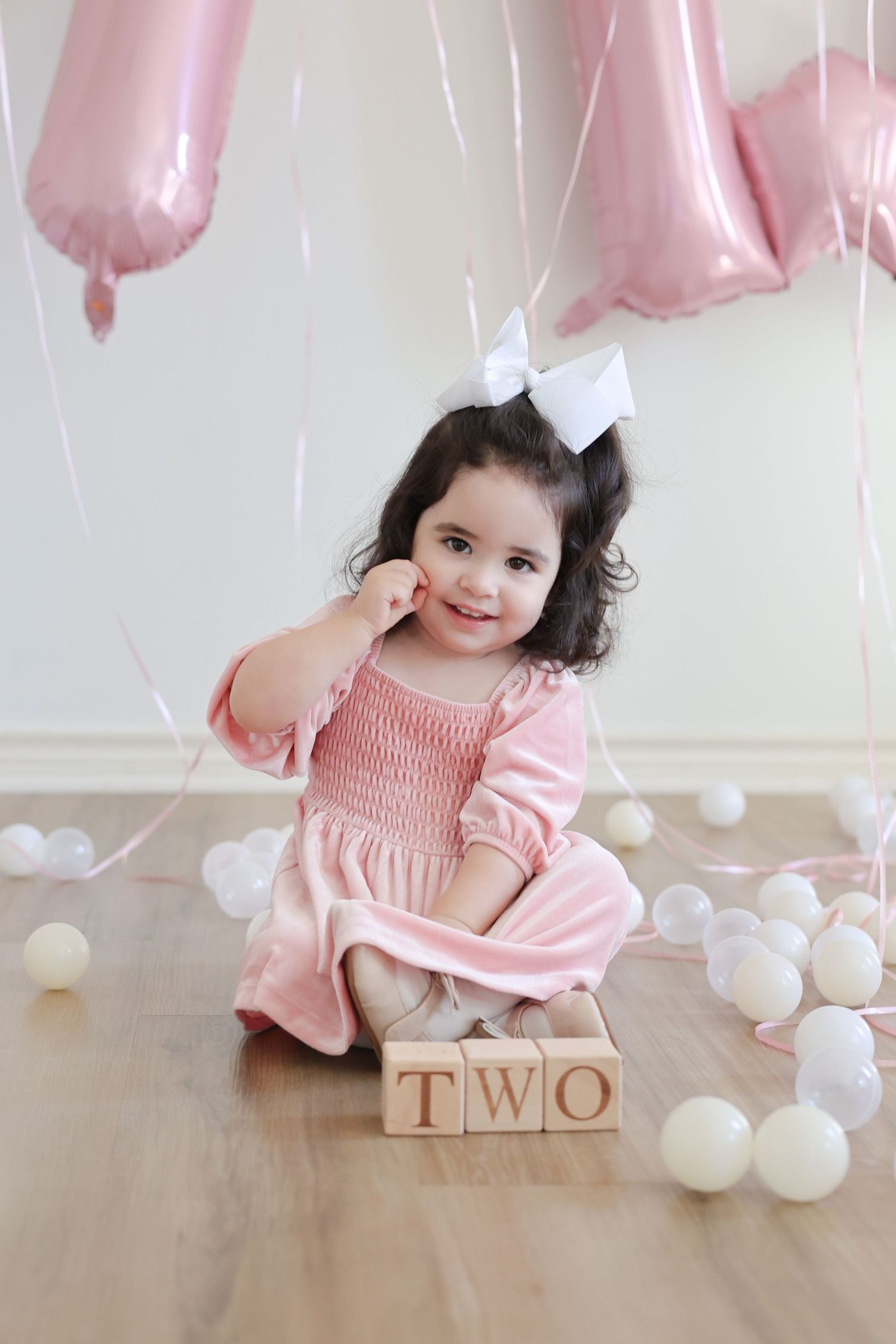 A toddler playing with blocks that spell out TWO during her 2nd birthday photoshoot in an indoor playroom in Austin, TX.