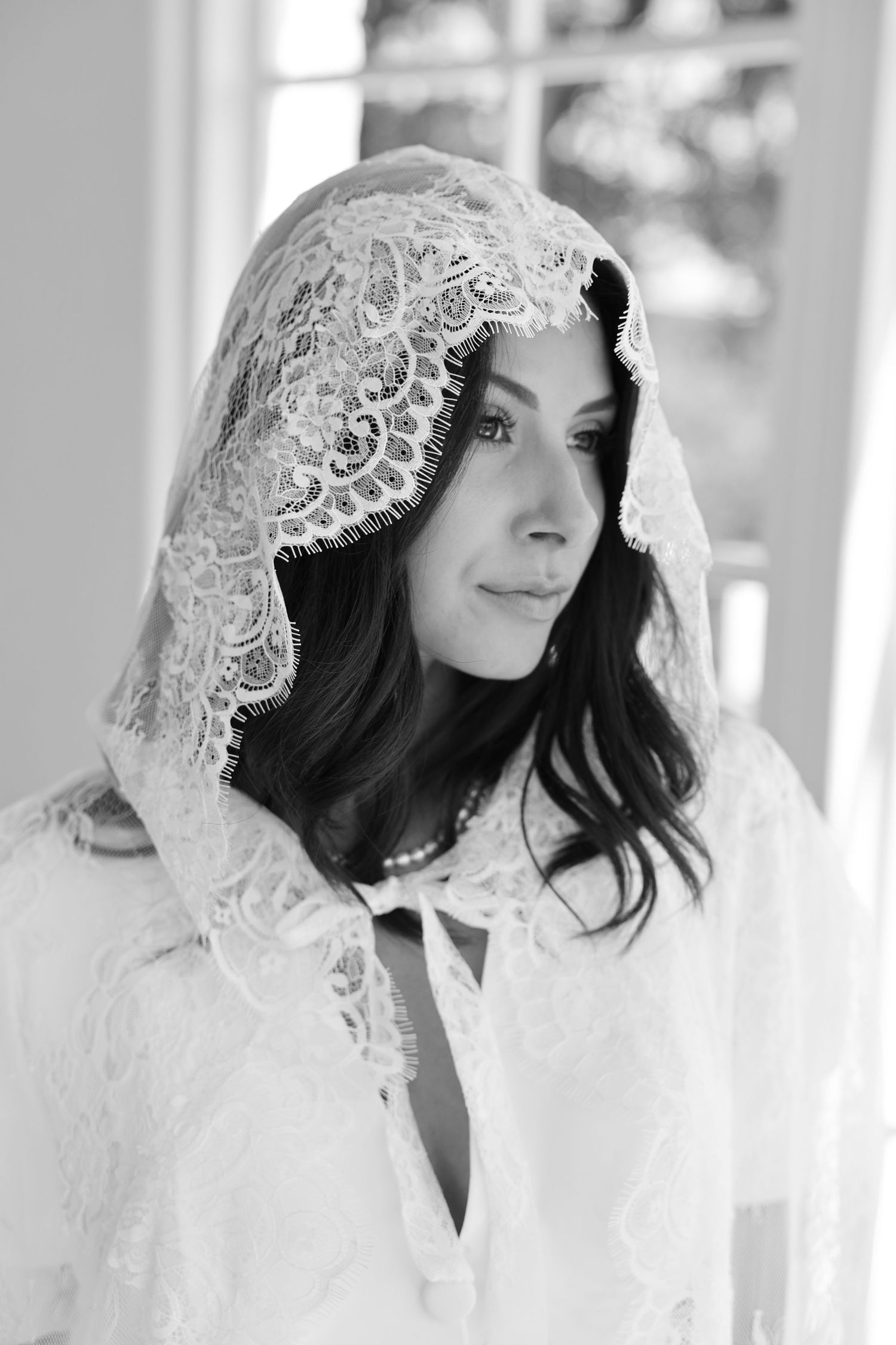 Black and white portrait of bride wearing vintage-style lace veil.