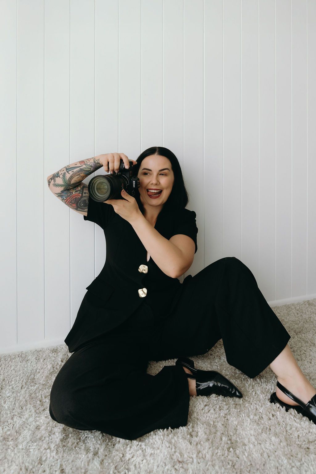 A person in black clothing lying on a white carpet holding a camera in three sequential poses.