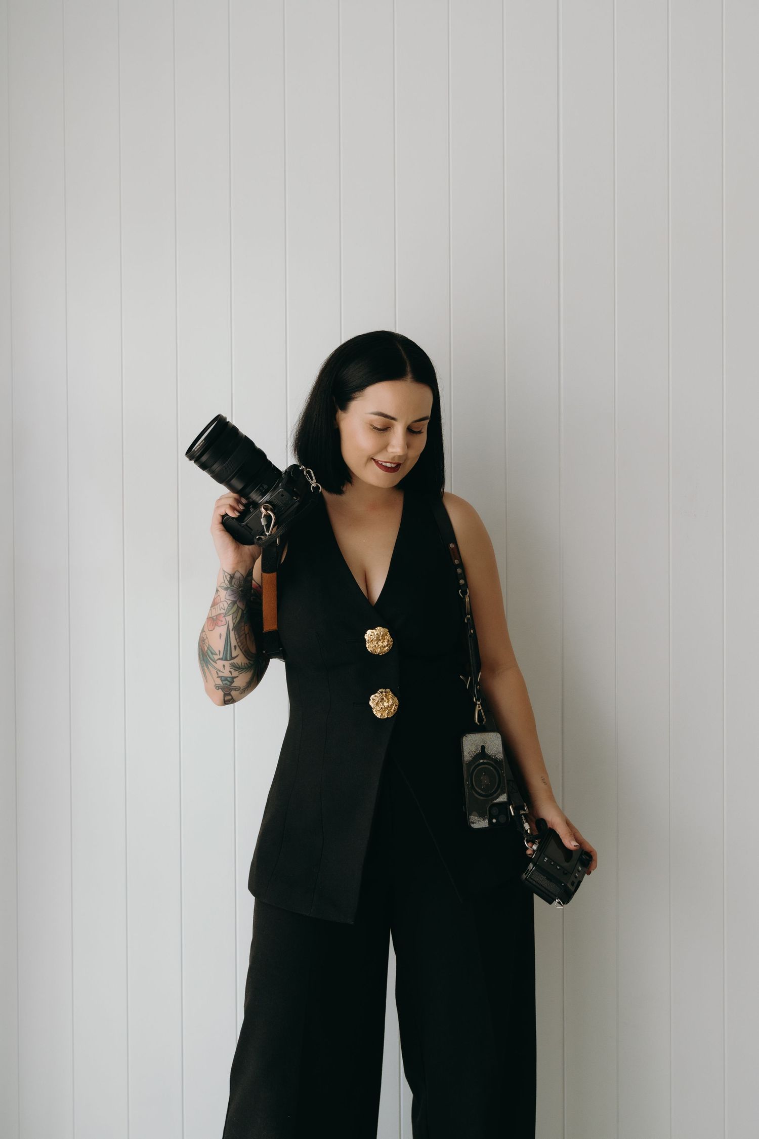 A photographer in a black sleeveless top poses with a camera against a white wall in a series of shots.