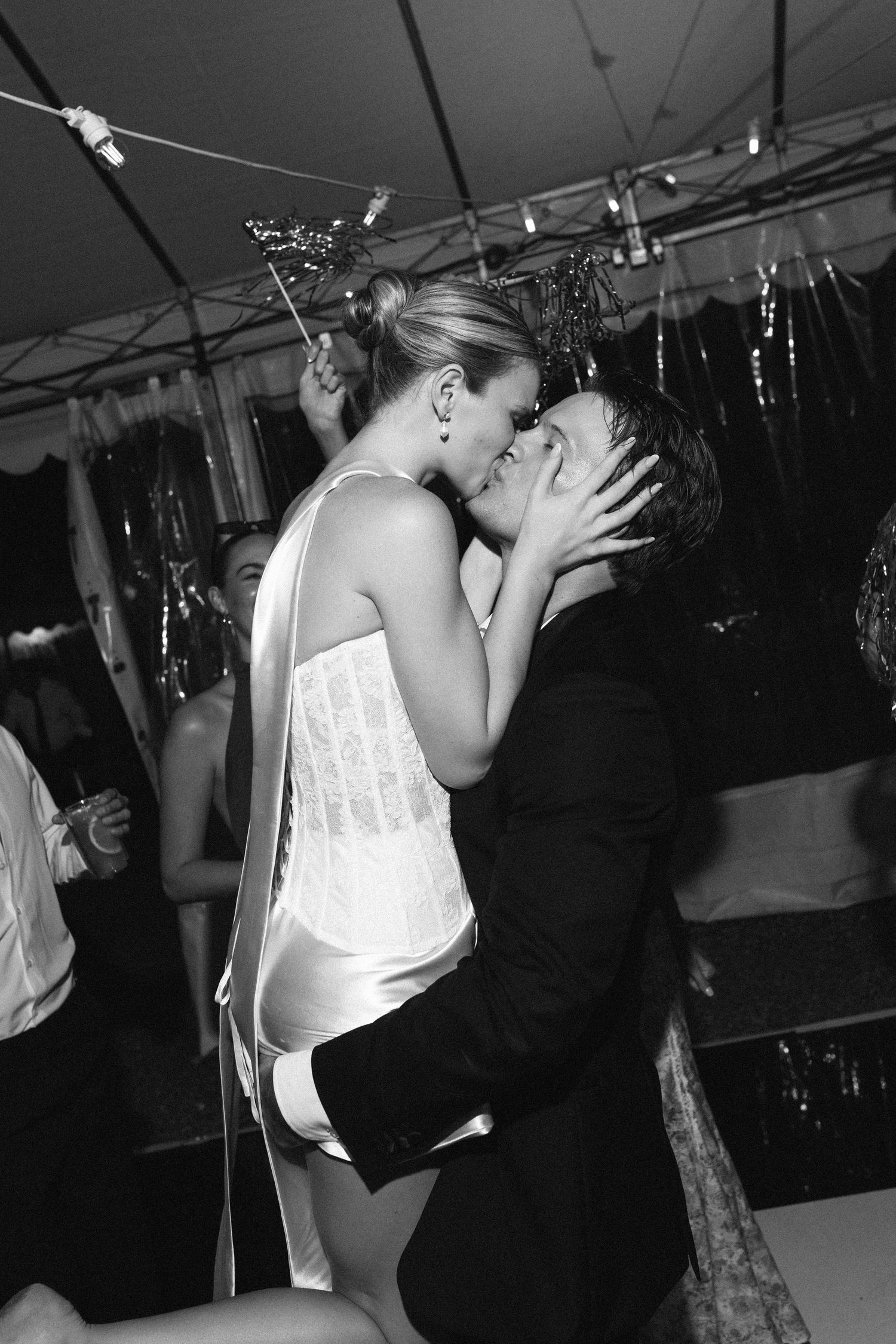 Couple sharing a romantic kiss at a New Year's Eve party in black and white photo.