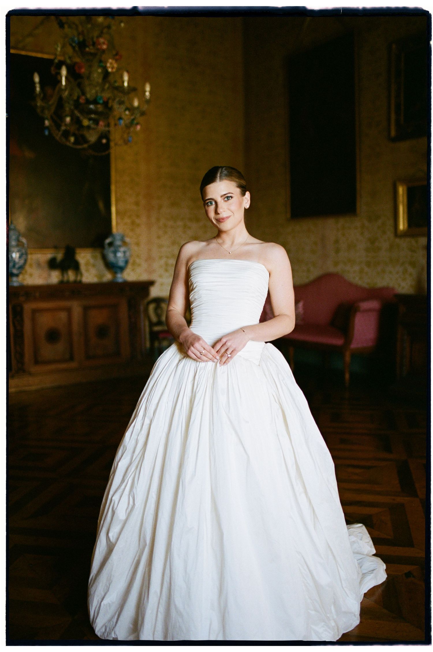 Elegant bride in a strapless ball gown posing in an ornate vintage room.