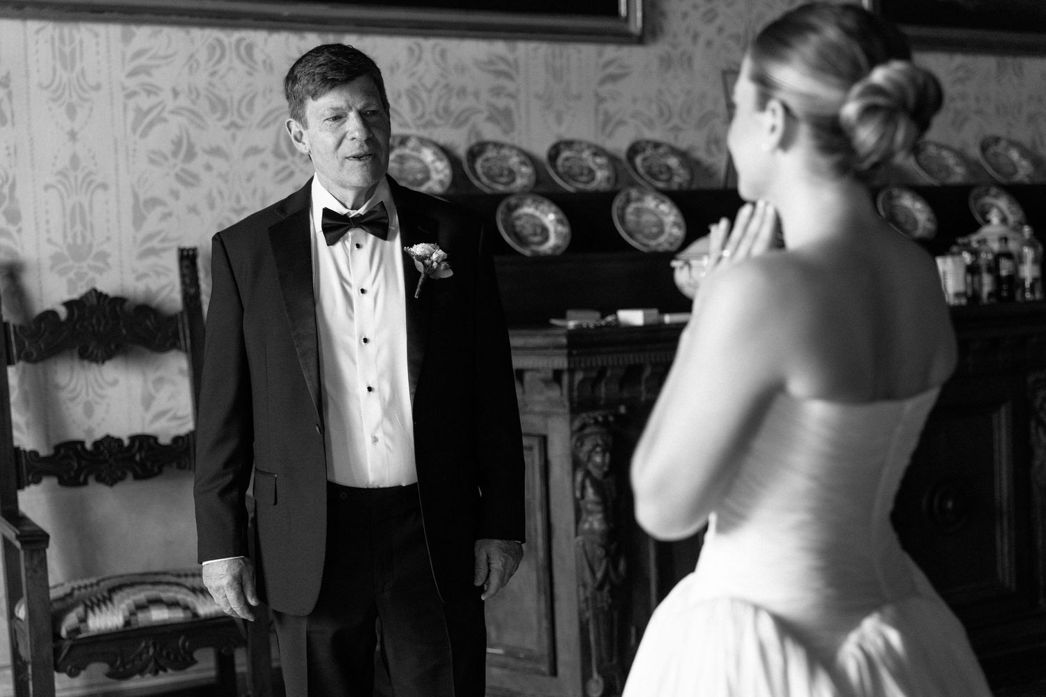 Black and white photo of groom seeing bride for first time, emotional first look moment at elegant wedding venue.