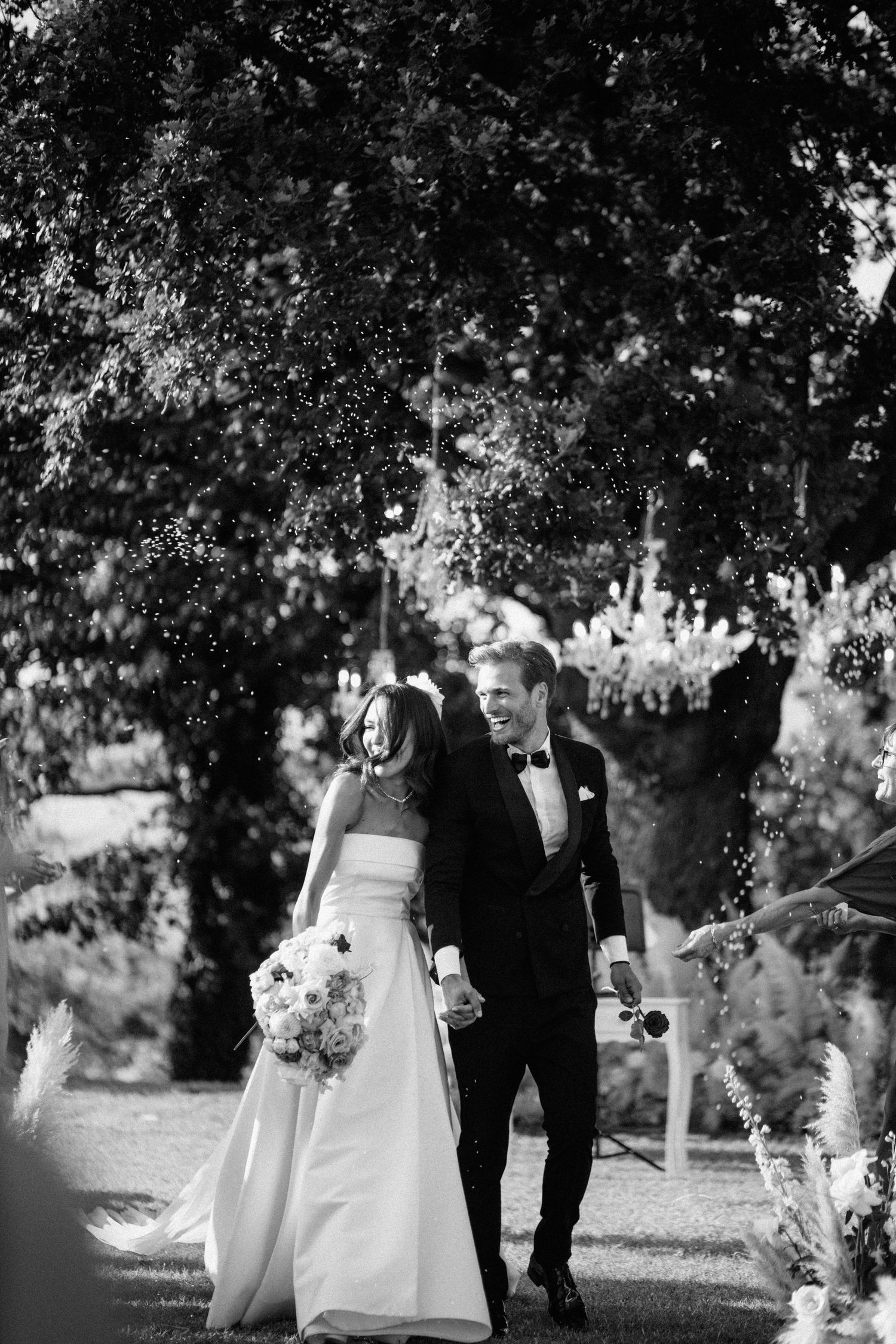 Black and white photo of smiling bride and groom walking together after ceremony.