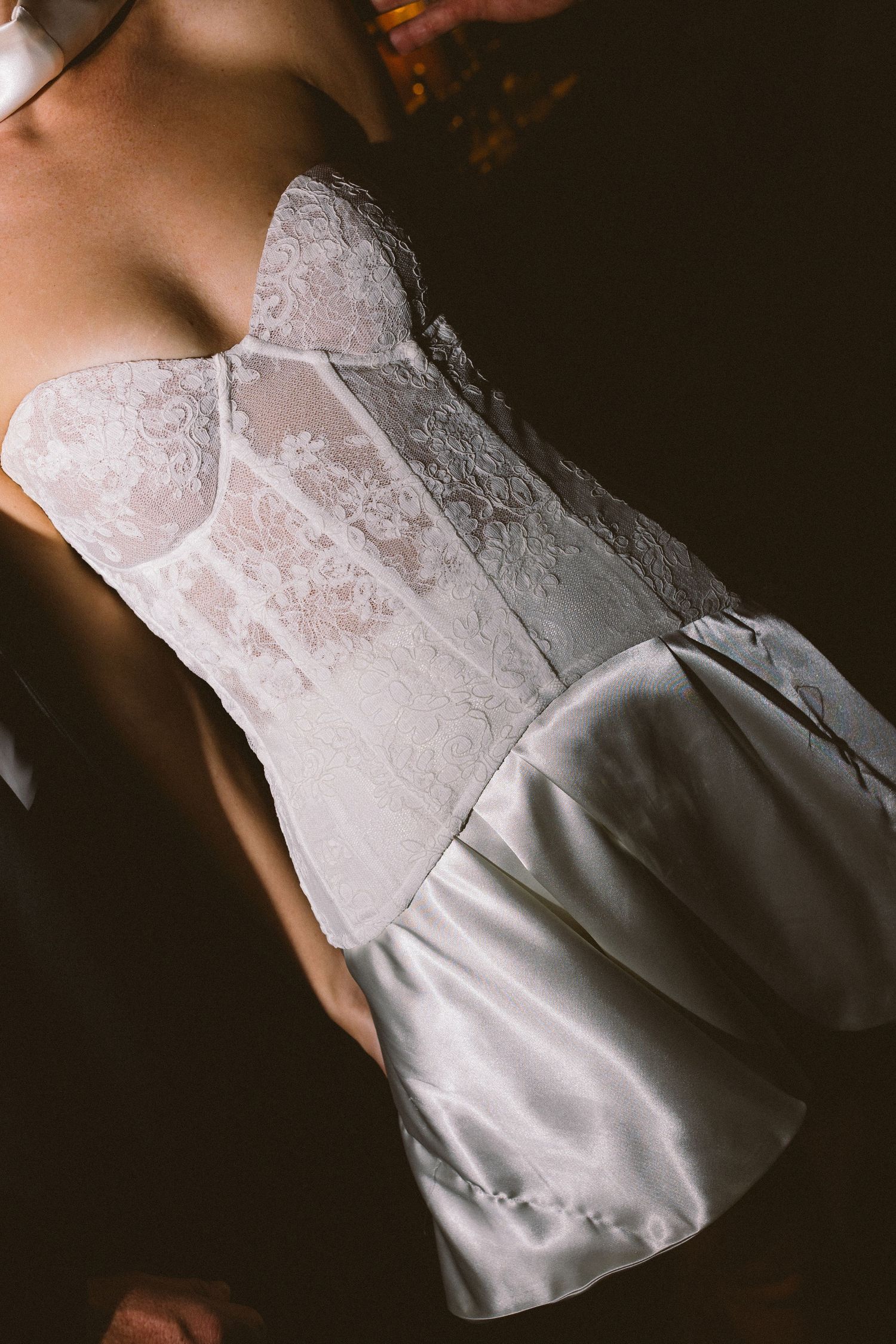 Elegant strapless lace corset wedding dress with satin skirt detail in soft white bridal fashion.