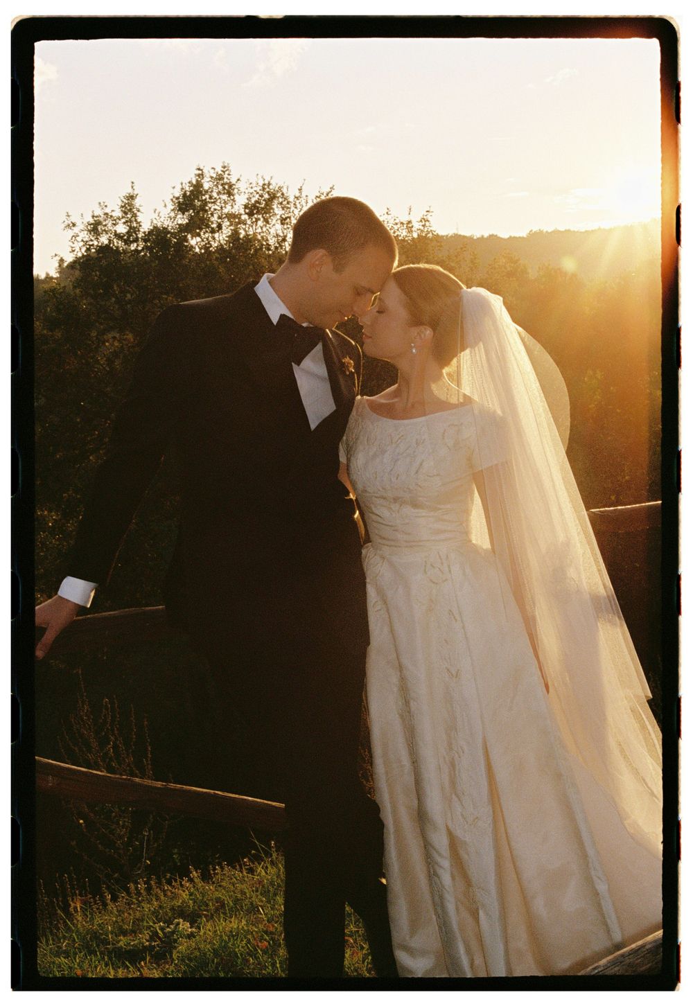 Bride and groom sharing a tender moment at golden sunset in a lush garden setting.