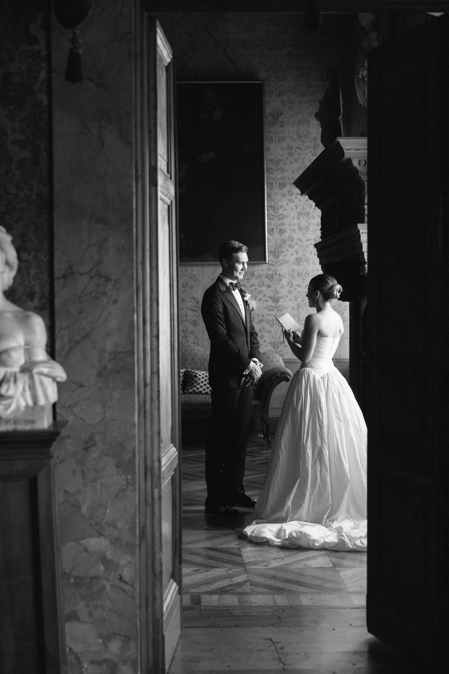 Black and white photo of bride and groom sharing a quiet moment in a grand marble-floored historic venue.