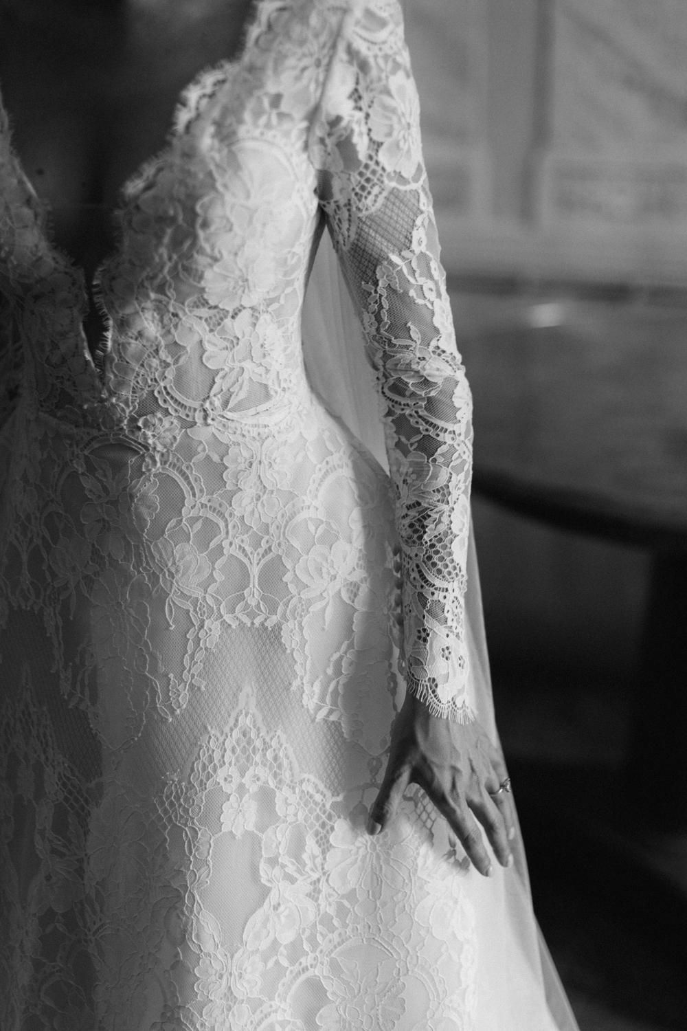 Close-up black and white detail of intricate lace long-sleeve wedding gown bodice.