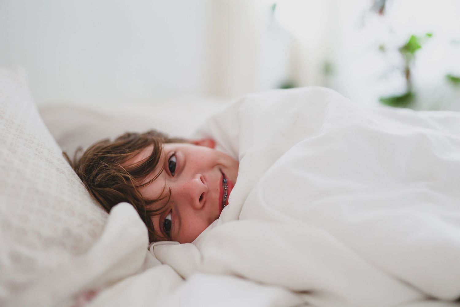 Person relaxing comfortably in white bedding.