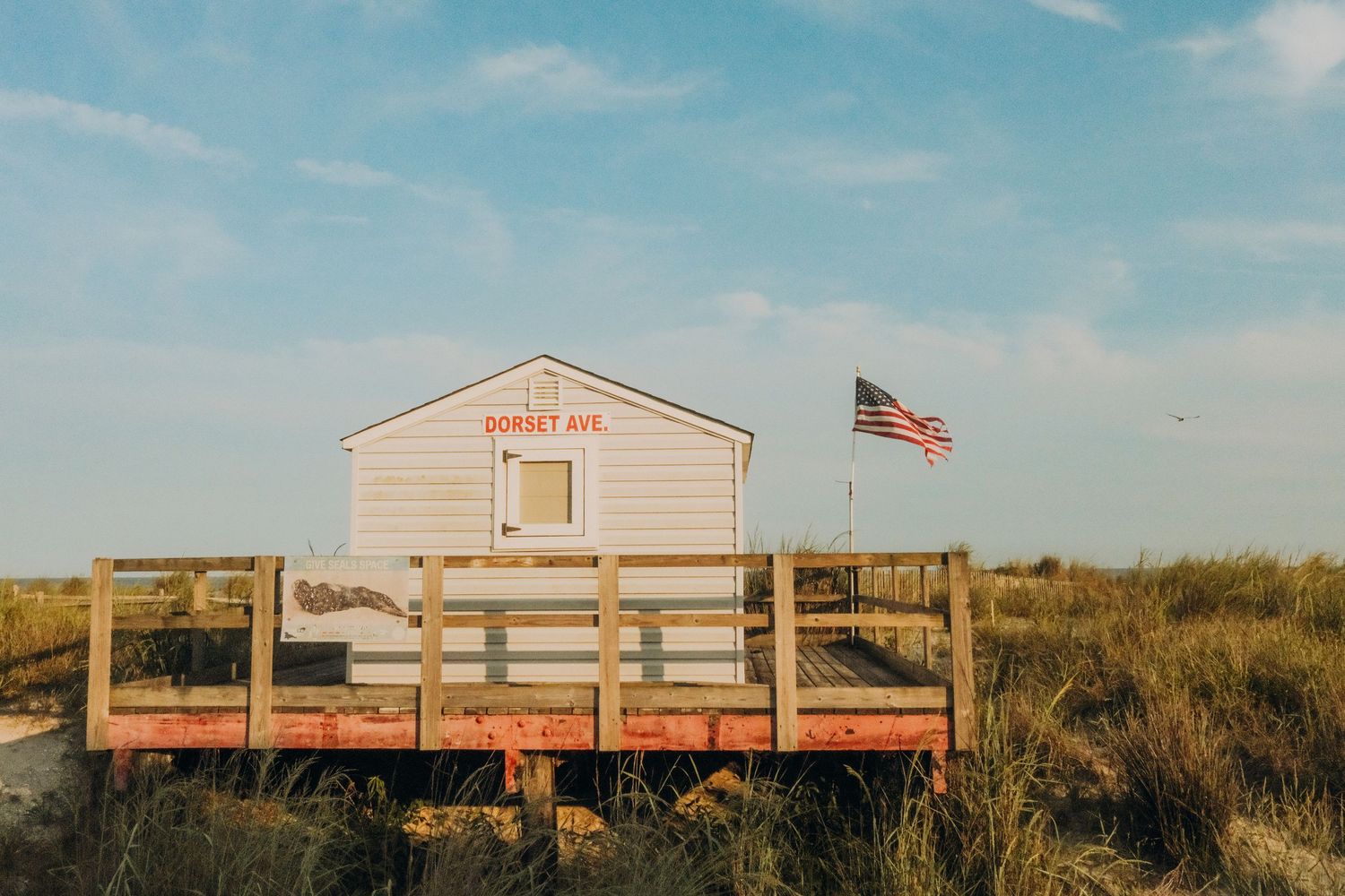 Row of beachfront buildings with an American flag flying under blue summer sky.