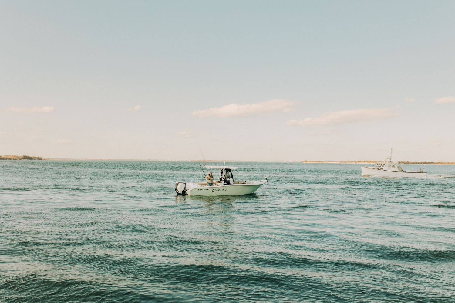 Aerial view of boats on calm blue ocean waters near the coastline.