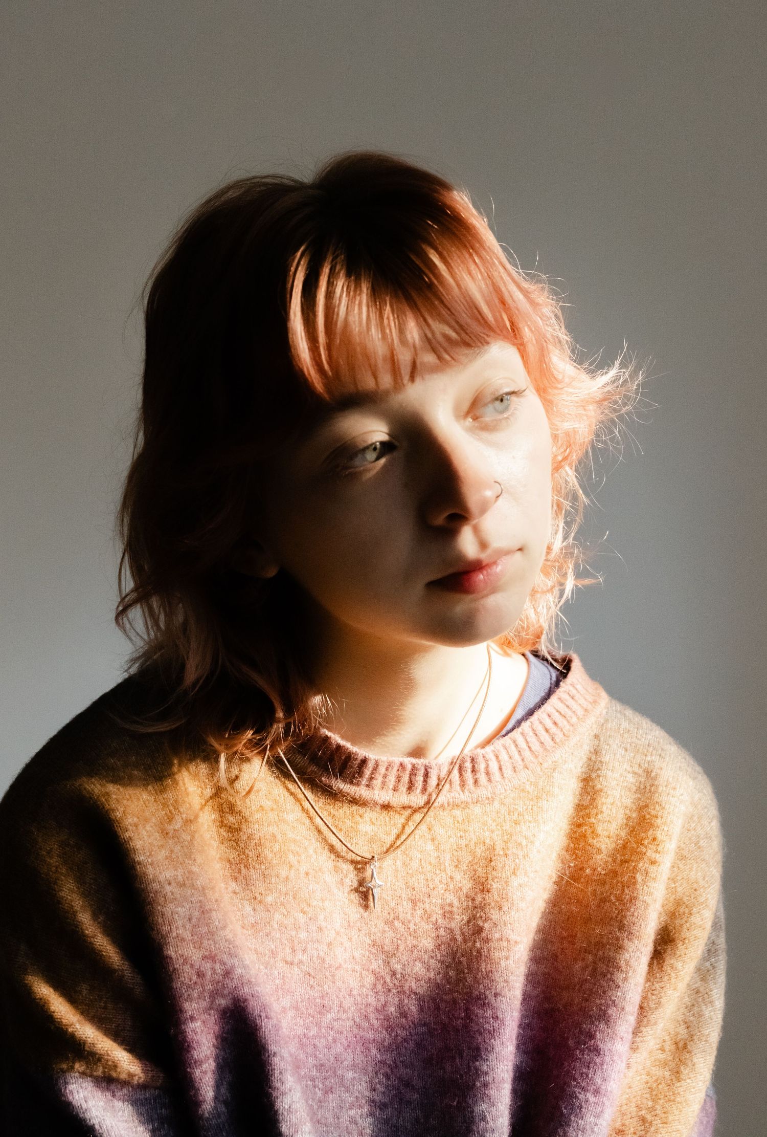 Artistic portrait in soft lighting featuring a person wearing a pastel gradient sweater.