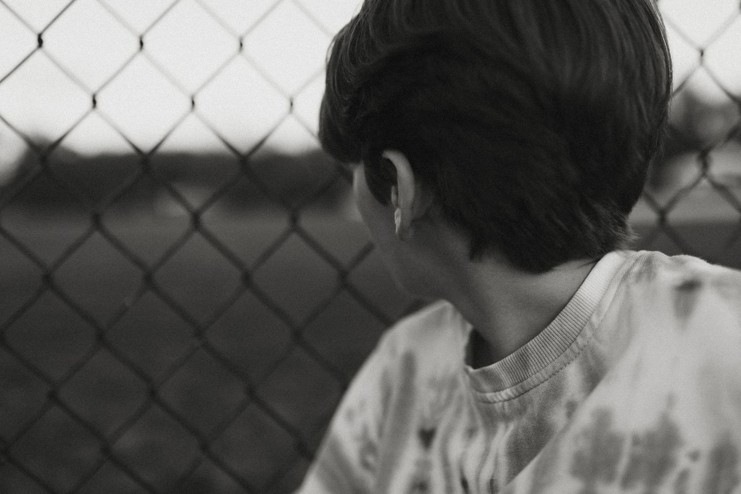 Black and white candid portraits against a chain link fence background.