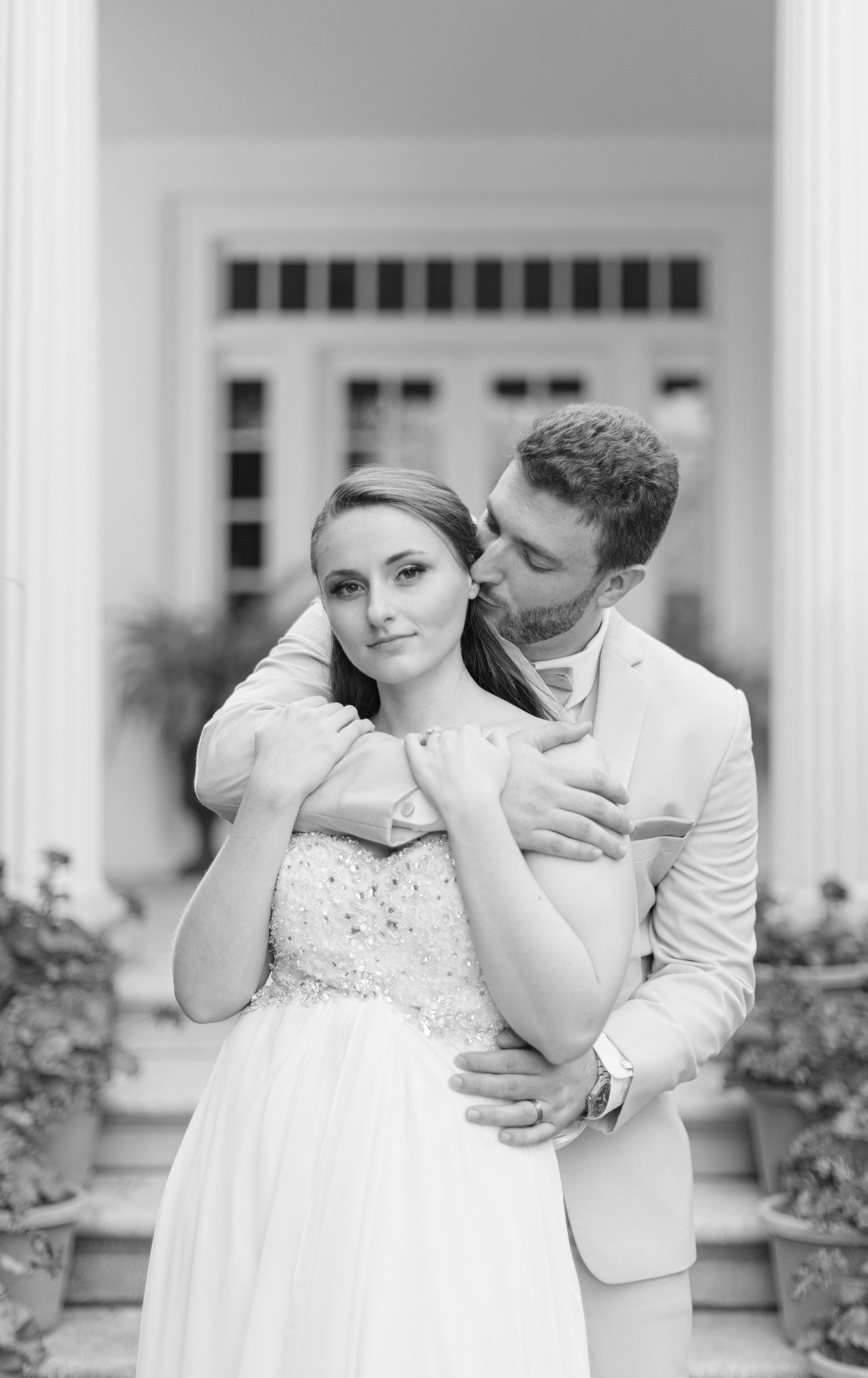 A black and white image of a groom embracing his bride from behind Cherry Hill NJ