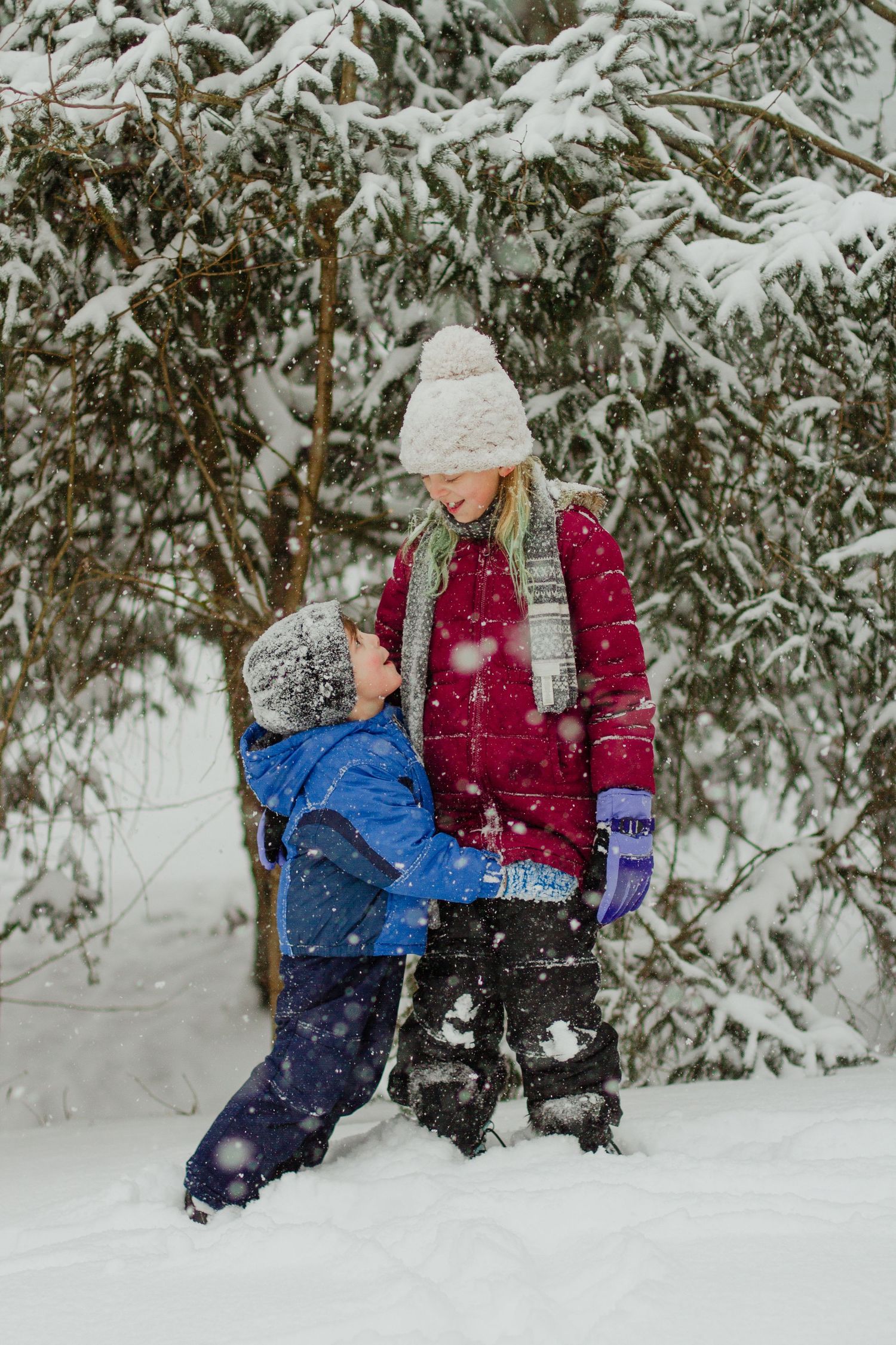 Two people playing together in a snowy winter forest landscape.