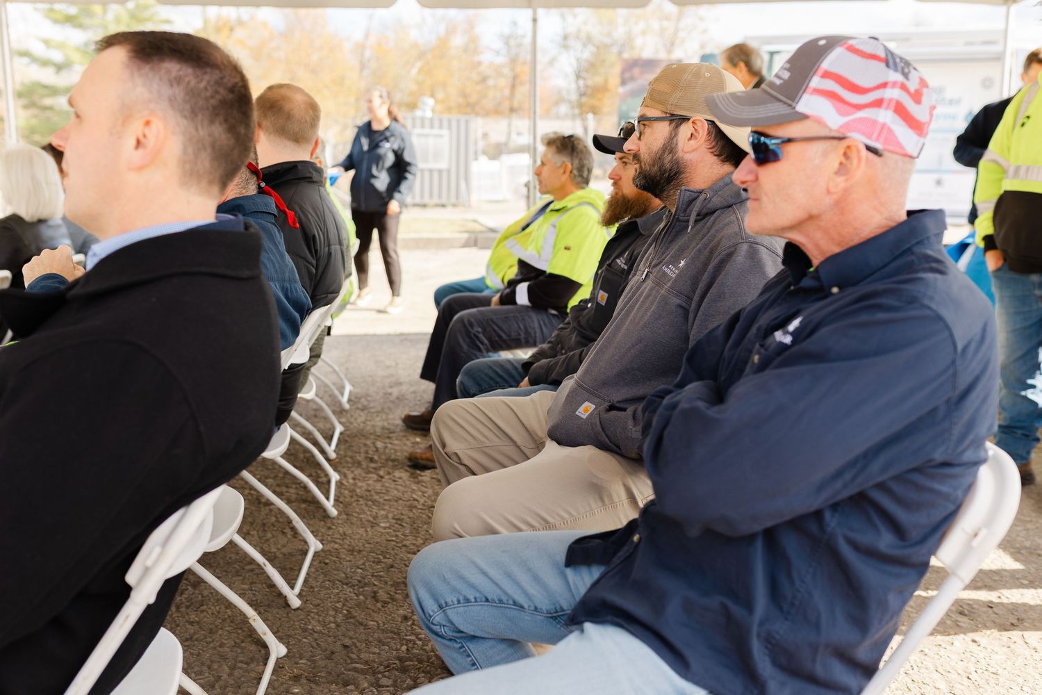 People seated in chairs at an outdoor gathering or ceremony.