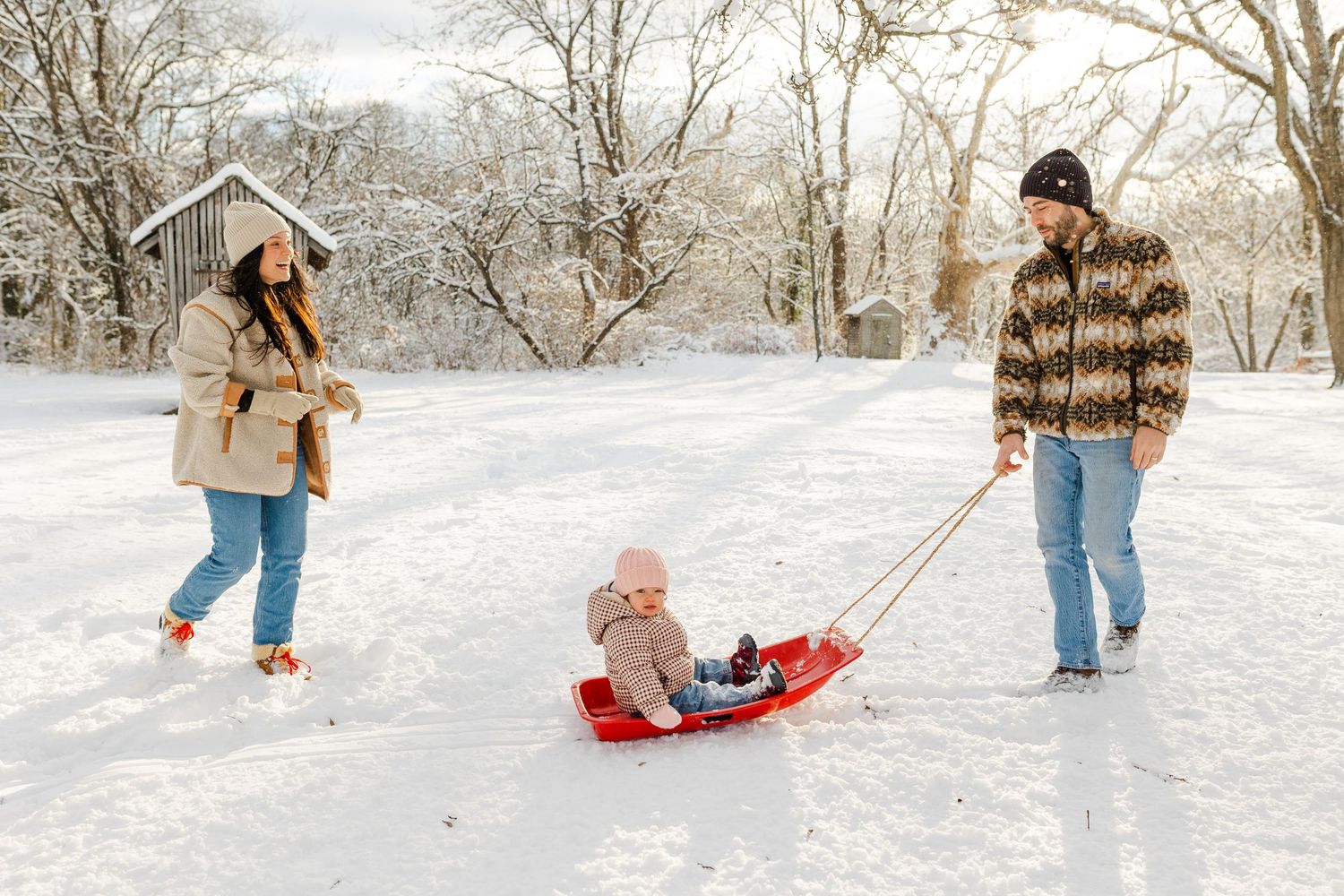 Winter scene of people sledding and playing in fresh snow.