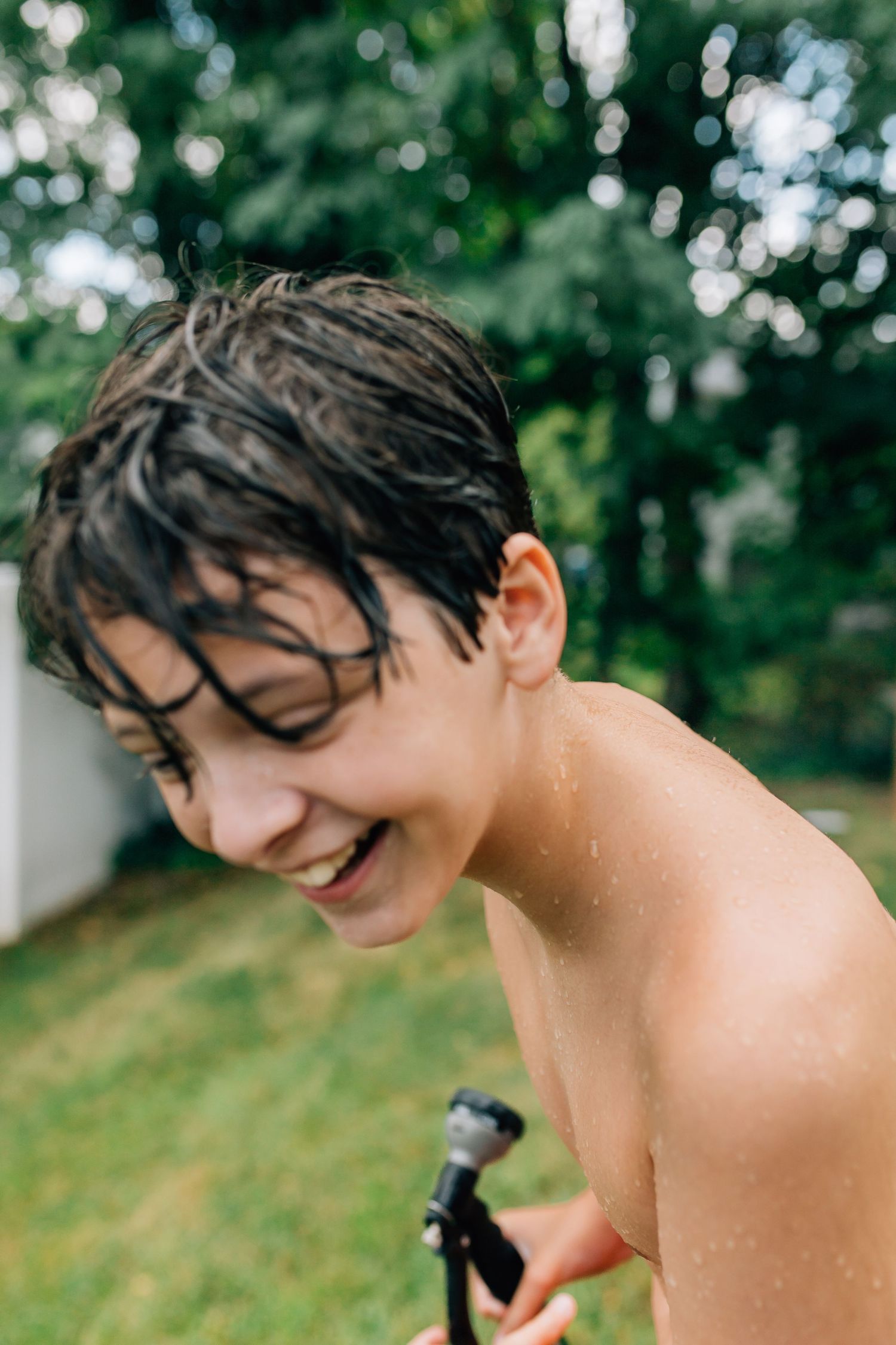 Close-up of wet hair and joyful expression while playing with water outdoors.