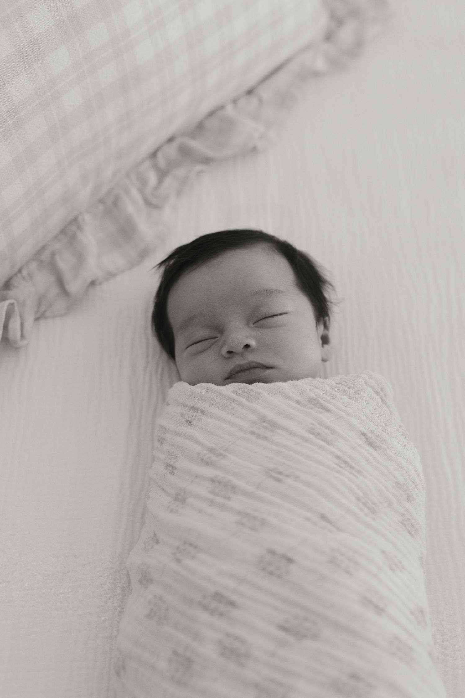 Black and white image of newborn baby sleeping in crib documentary photography cherry hill new jersey
