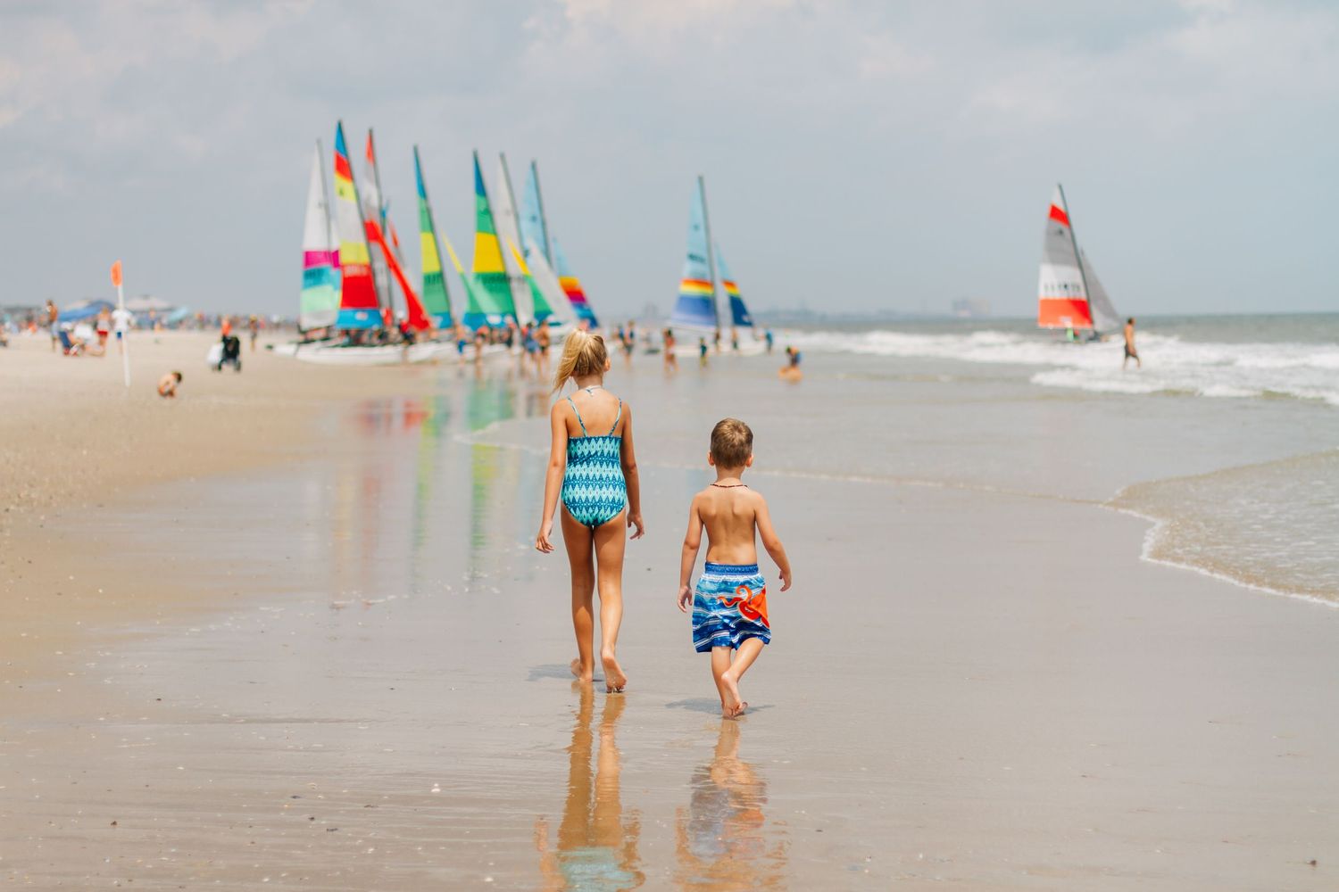 Beach scene with colorful umbrellas and people enjoying the ocean.