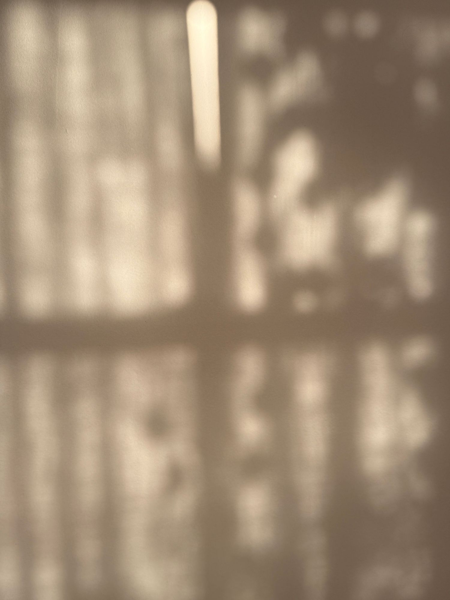 Abstract pattern of sunlight and shadows creating geometric shapes on a wall.