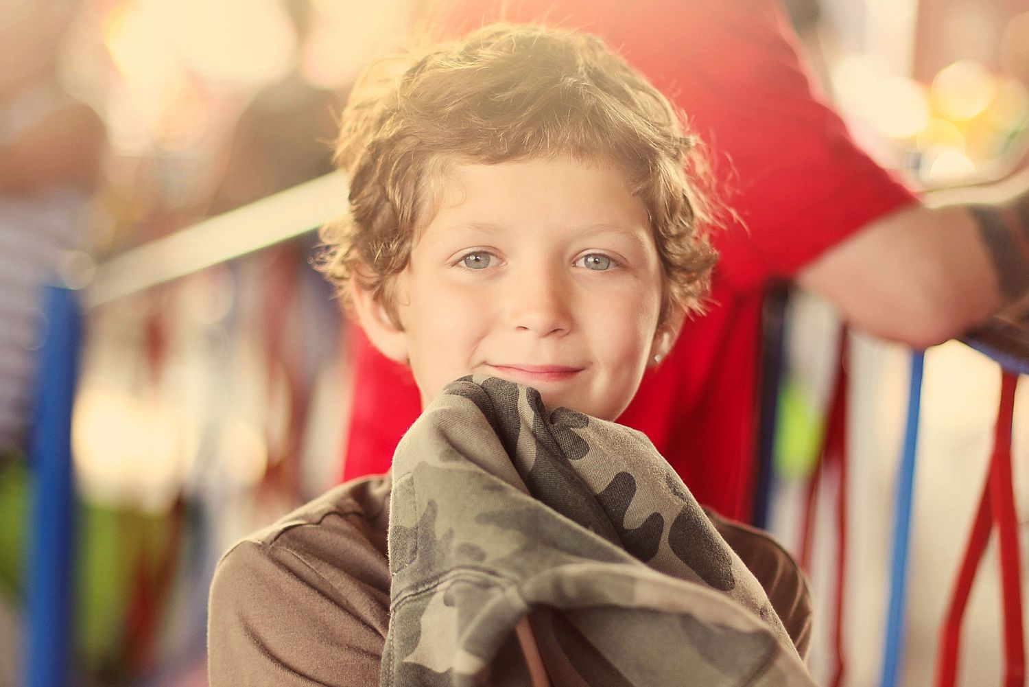Child with curly hair smiling in front of colorful bookshelves.