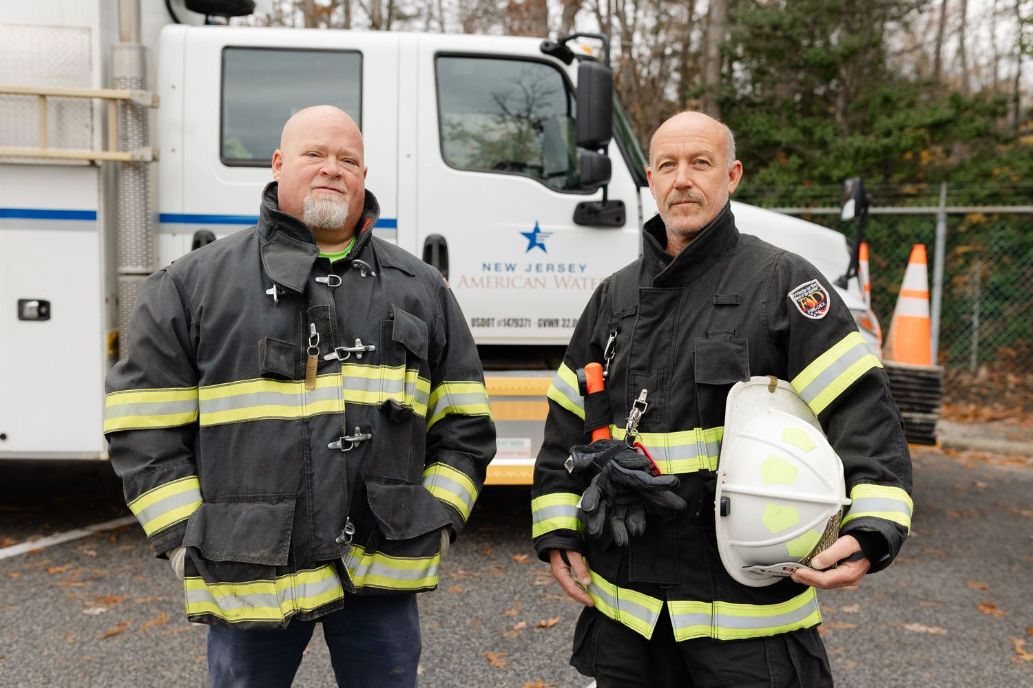Group of firefighters in protective gear standing together outdoors.