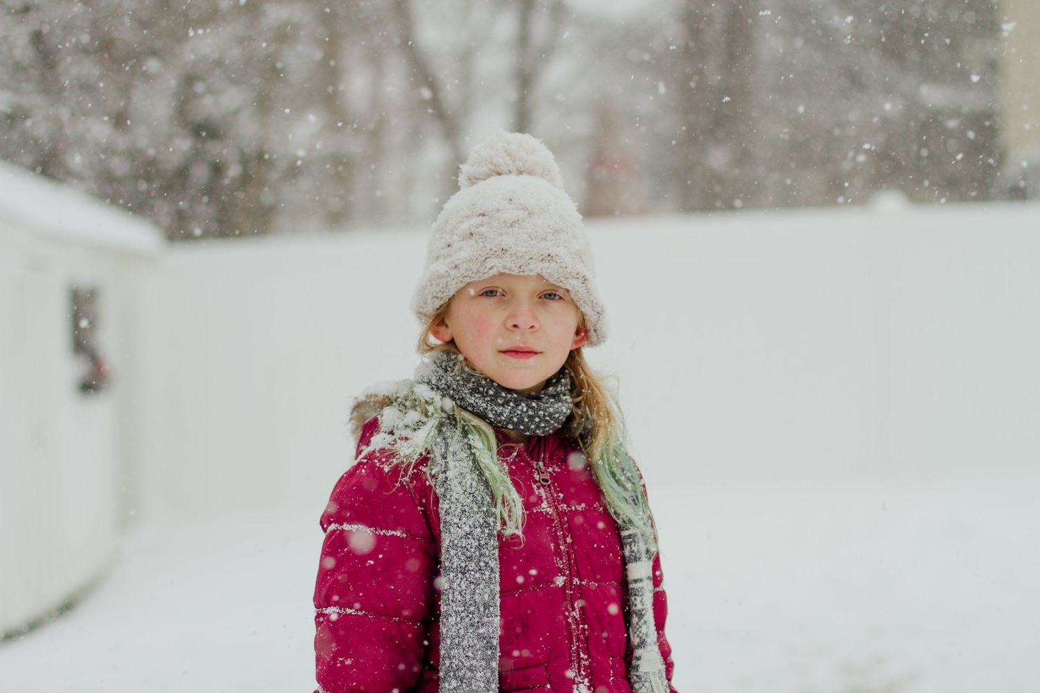Person bundled up in winter clothing walking through falling snow.