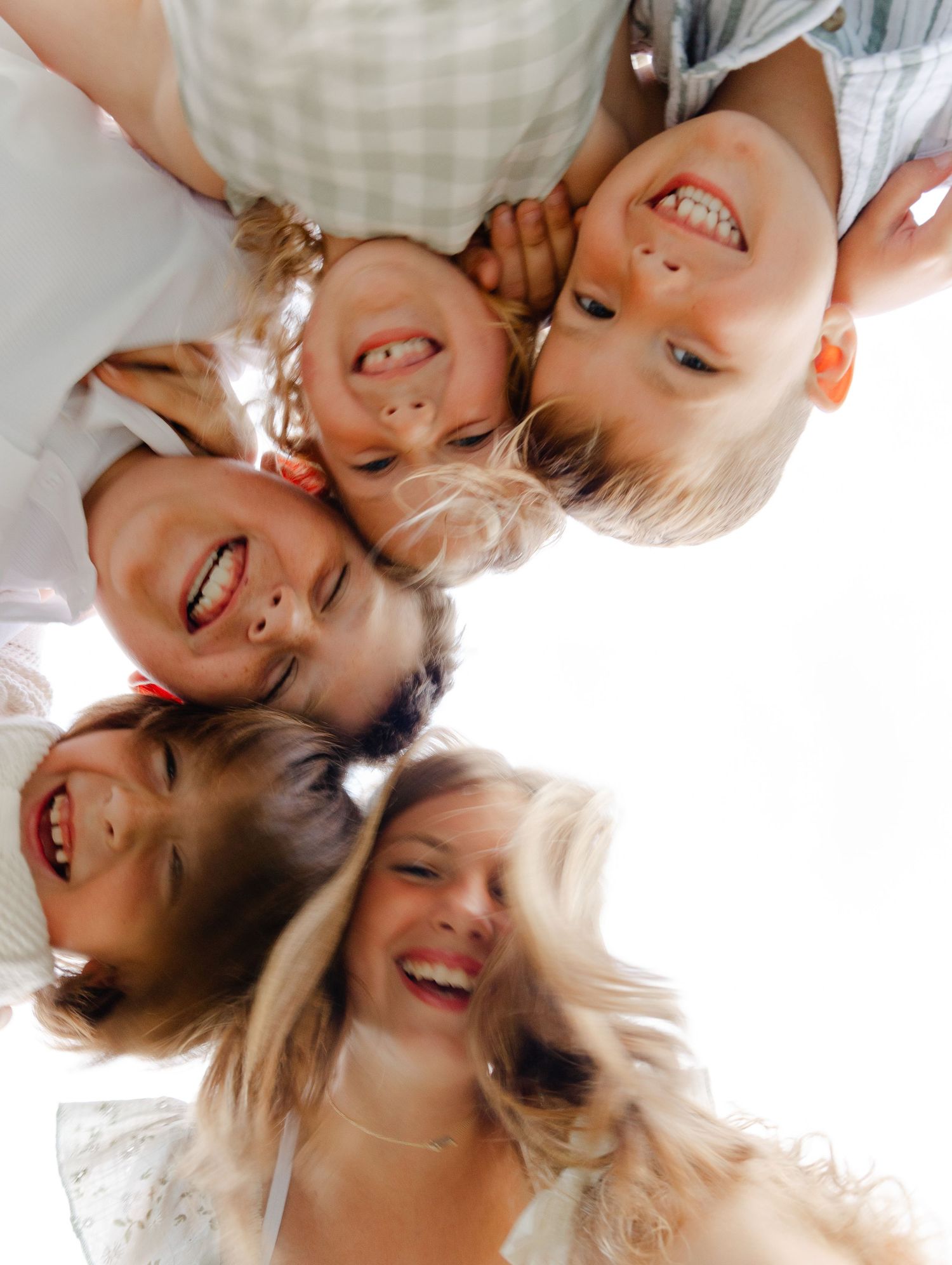 Joyful family huddle viewed from below with mother and children smiling and laughing.