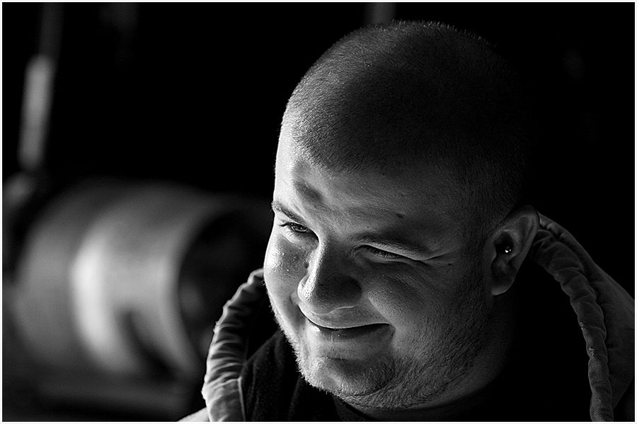 Black and white close-up portrait of a bald man smiling warmly with a blurred background.
