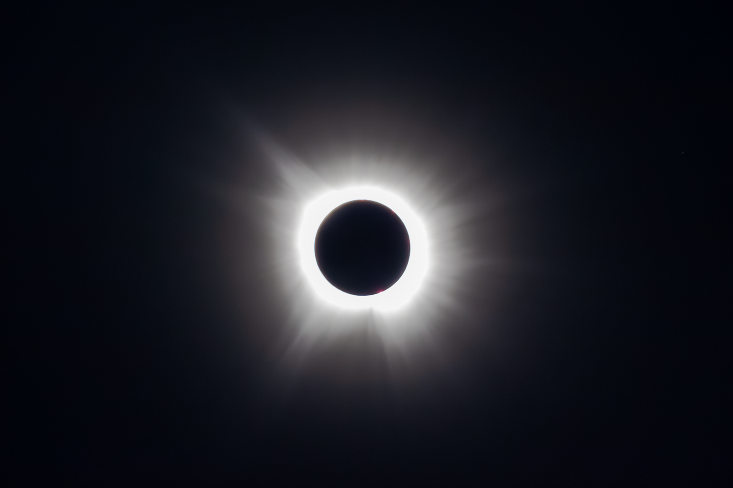 A stunning total solar eclipse showing the sun's glowing white corona against a dark sky.