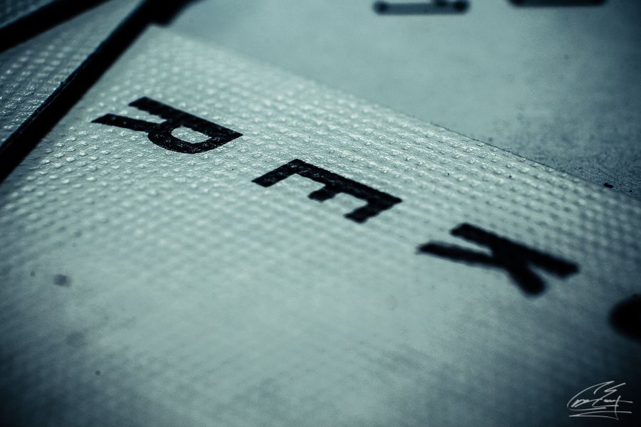 Macro close-up of embossed black letters on a textured gray surface with shallow depth.