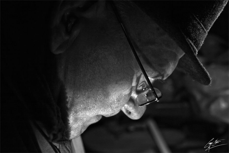 Black and white close-up of a person wearing a hat holding a thin rod or cane.