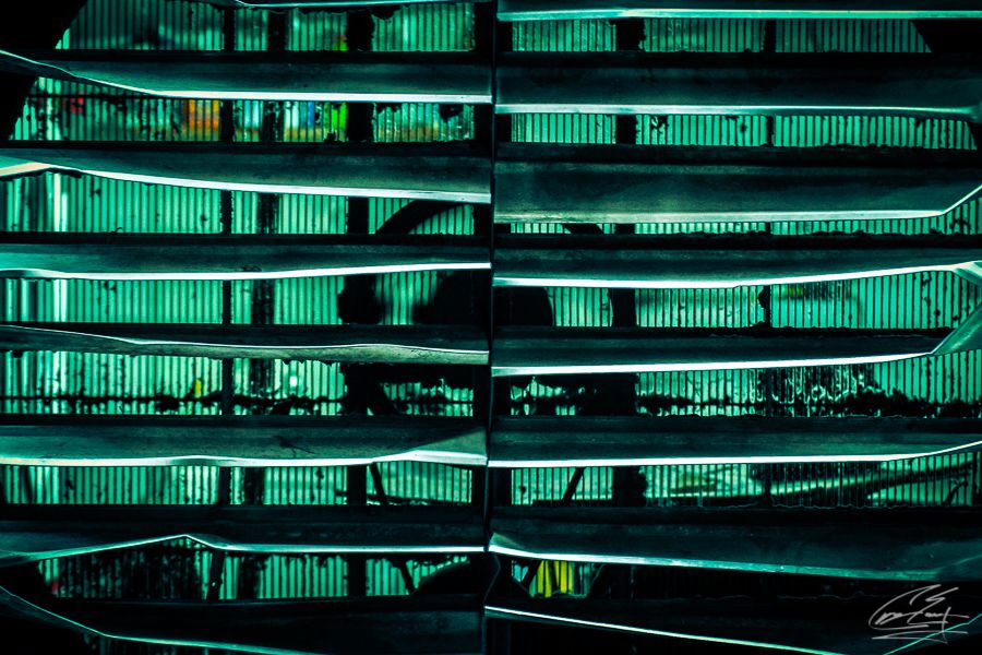 Abstract architectural photo of a building facade illuminated with glowing green neon lights at night.