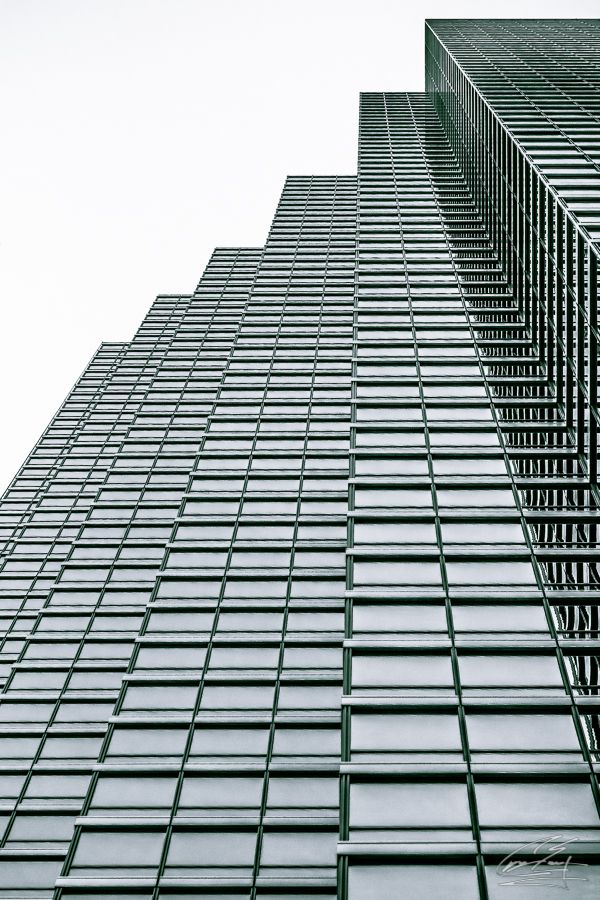 Low angle view looking up at modern glass skyscraper facade with geometric grid pattern windows.