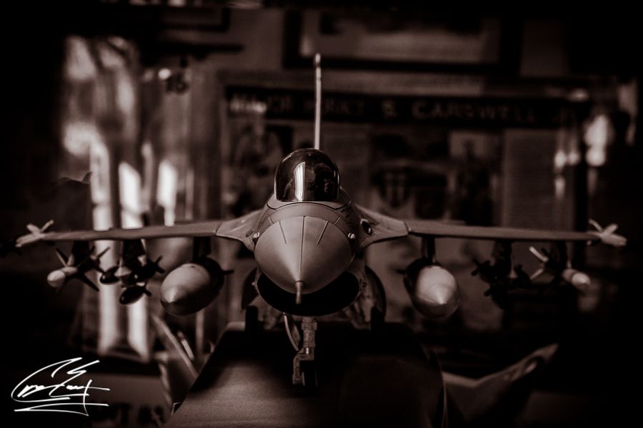 A detailed scale model of an F-16 fighter jet displayed in sepia tone photography.