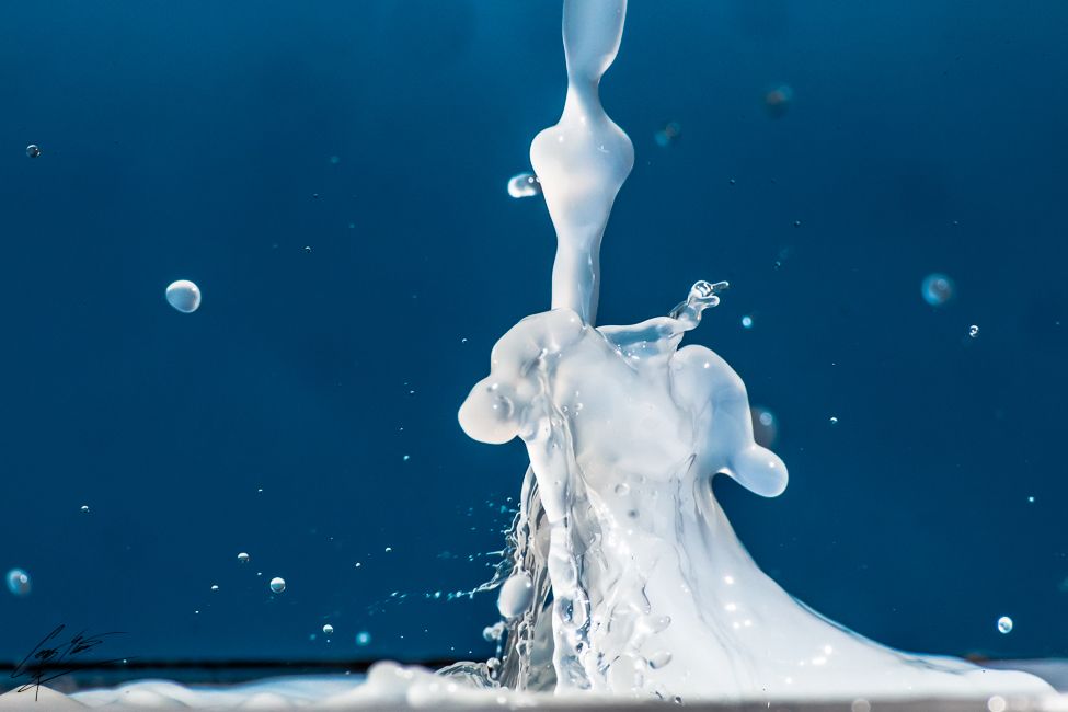 High-speed macro photo of white milk splash frozen in motion against a vivid blue background.