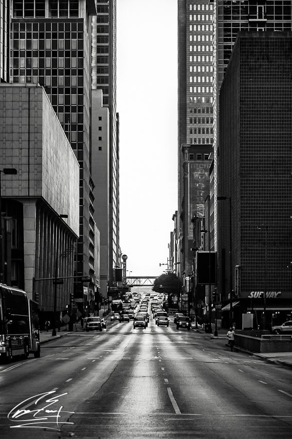 Black and white urban street photography of busy city avenue lined with skyscrapers.
