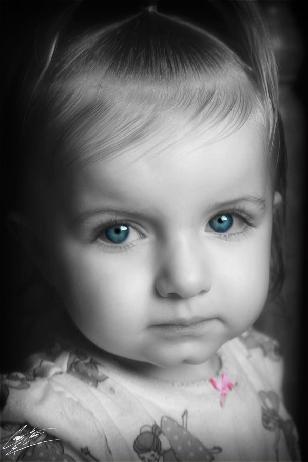 Black and white portrait of a young toddler girl with striking vivid blue eyes gazing softly.