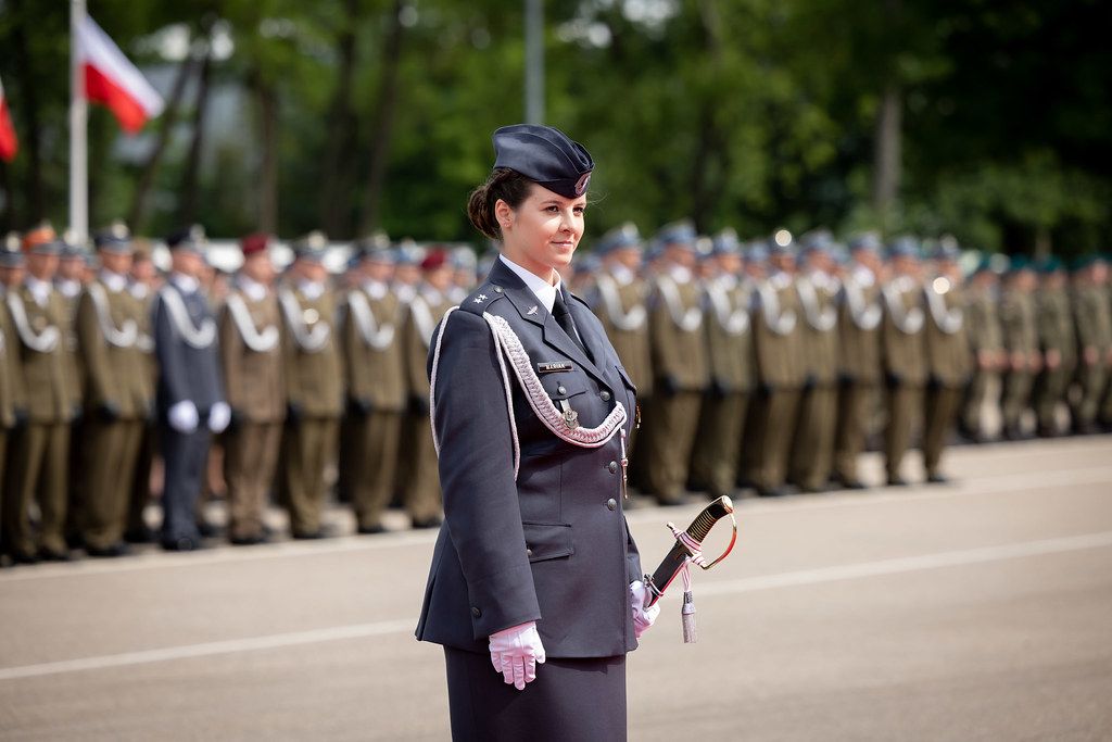 Female military officer in dress uniform standing at formal parade.