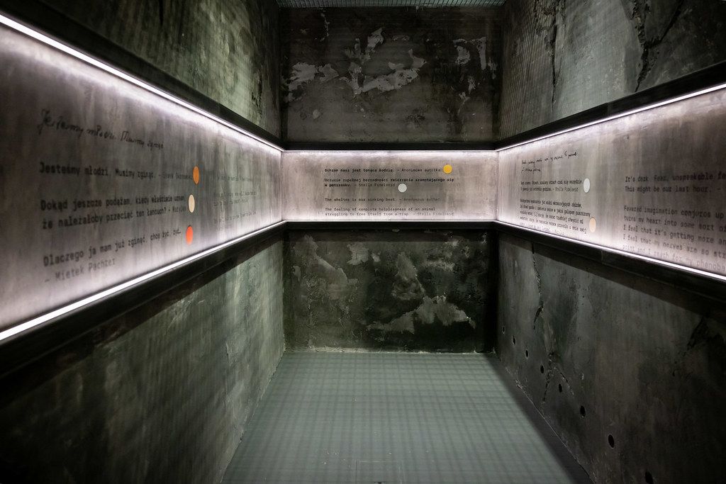 Empty memorial room with illuminated text inscriptions on concrete walls.