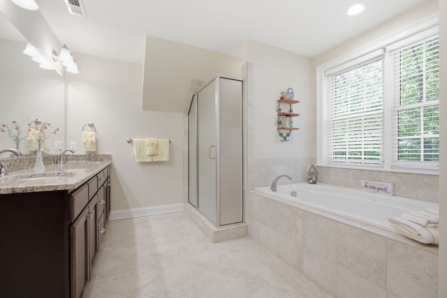 Luxurious master bathroom with dual vanity, soaking tub, glass shower, and tile floors.