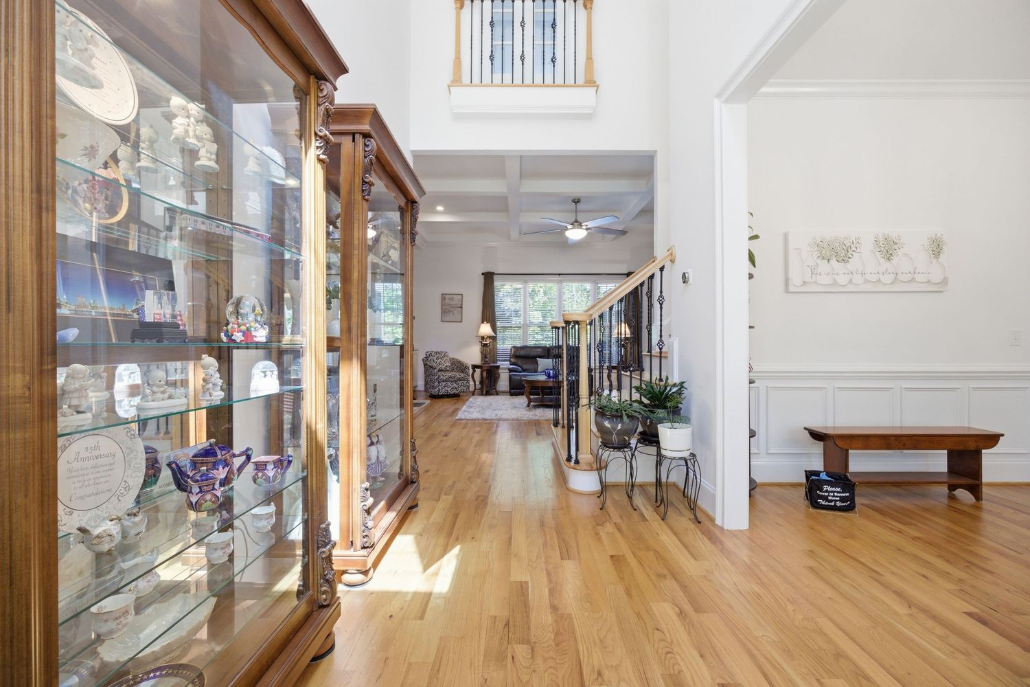 Grand foyer with hardwood floors, display cabinet, wainscoting, and staircase leading upstairs.