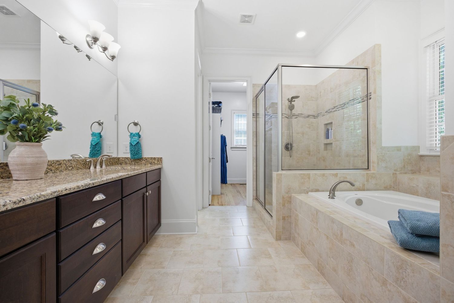 Luxurious master bathroom with dark vanity, granite counters, soaking tub, and glass-enclosed shower.
