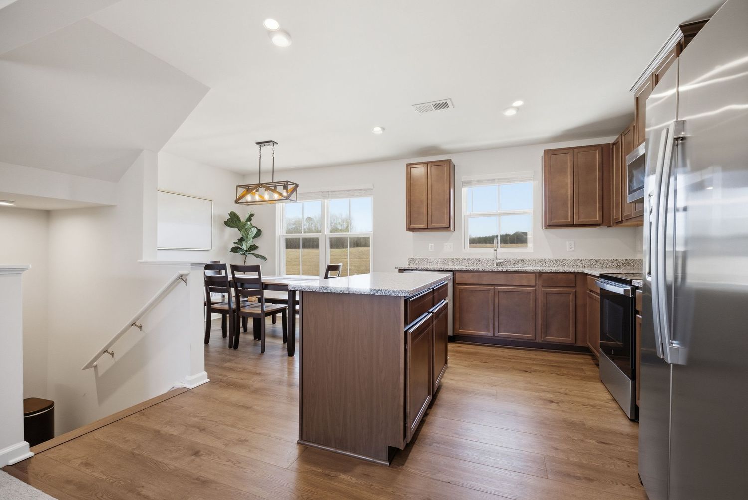 Modern kitchen with brown cabinets, island, stainless steel appliances, and view into dining area.