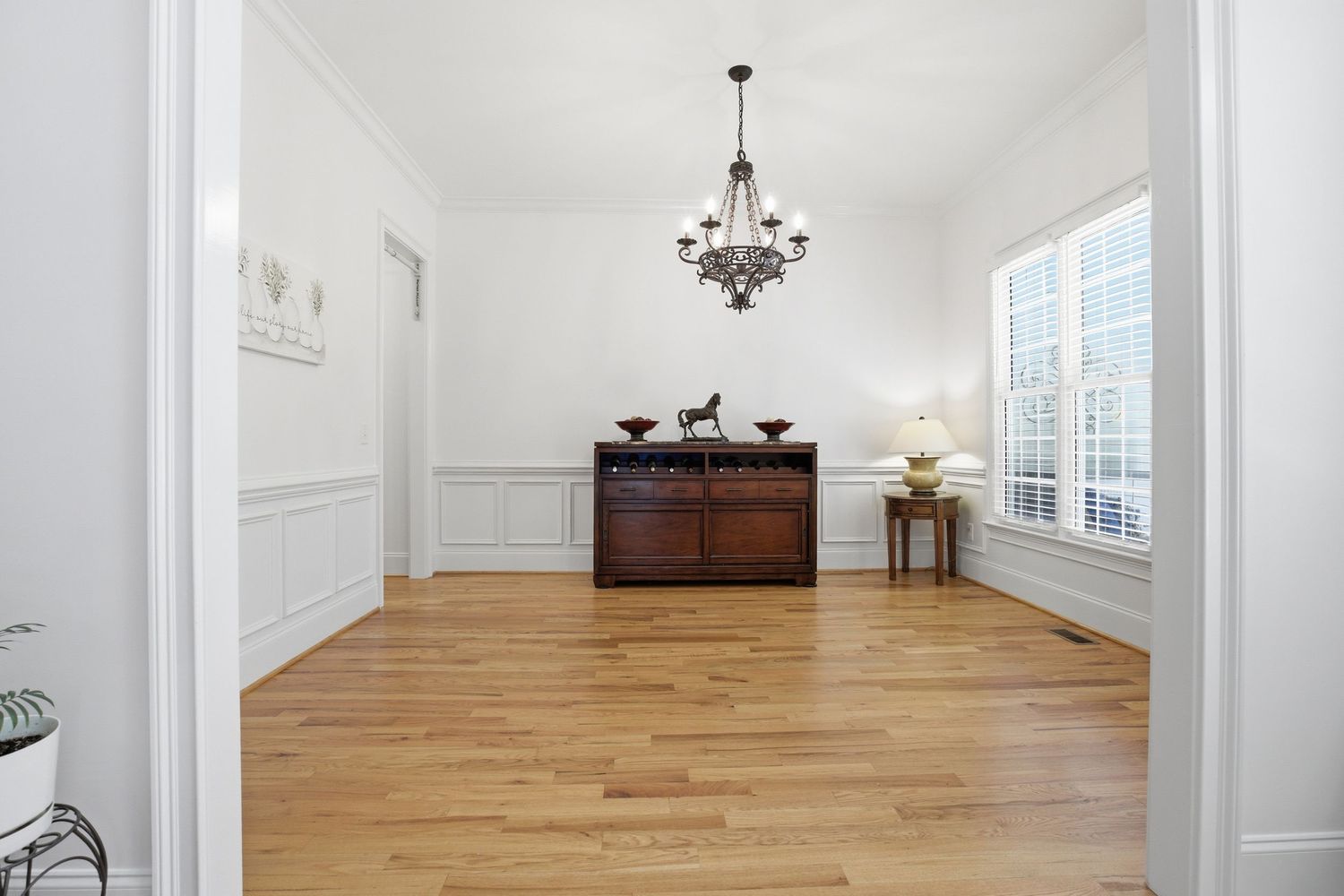 Elegant foyer with hardwood floors, wainscoting, chandelier, and antique wooden dresser.