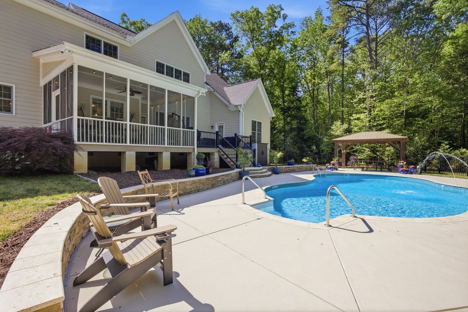 Backyard patio with Adirondack chairs and round swimming pool surrounded by lush trees and screened porch.