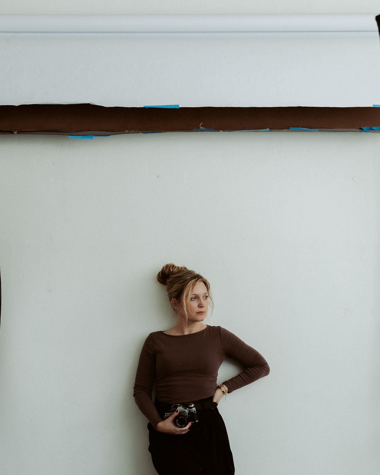 photo of ash coniglio against a white wall holding a camera