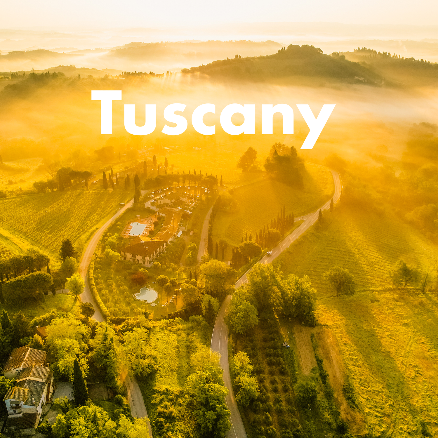 Aerial view of golden misty rolling hills and vineyards of Tuscany, Italy at sunrise.