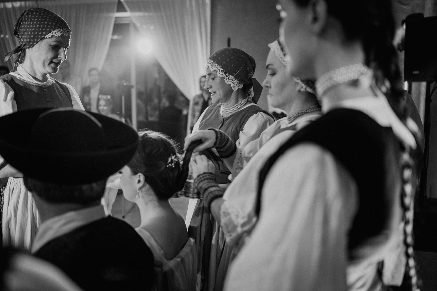 Black and white photo of people in traditional folk costumes gathered at a cultural event or festival.